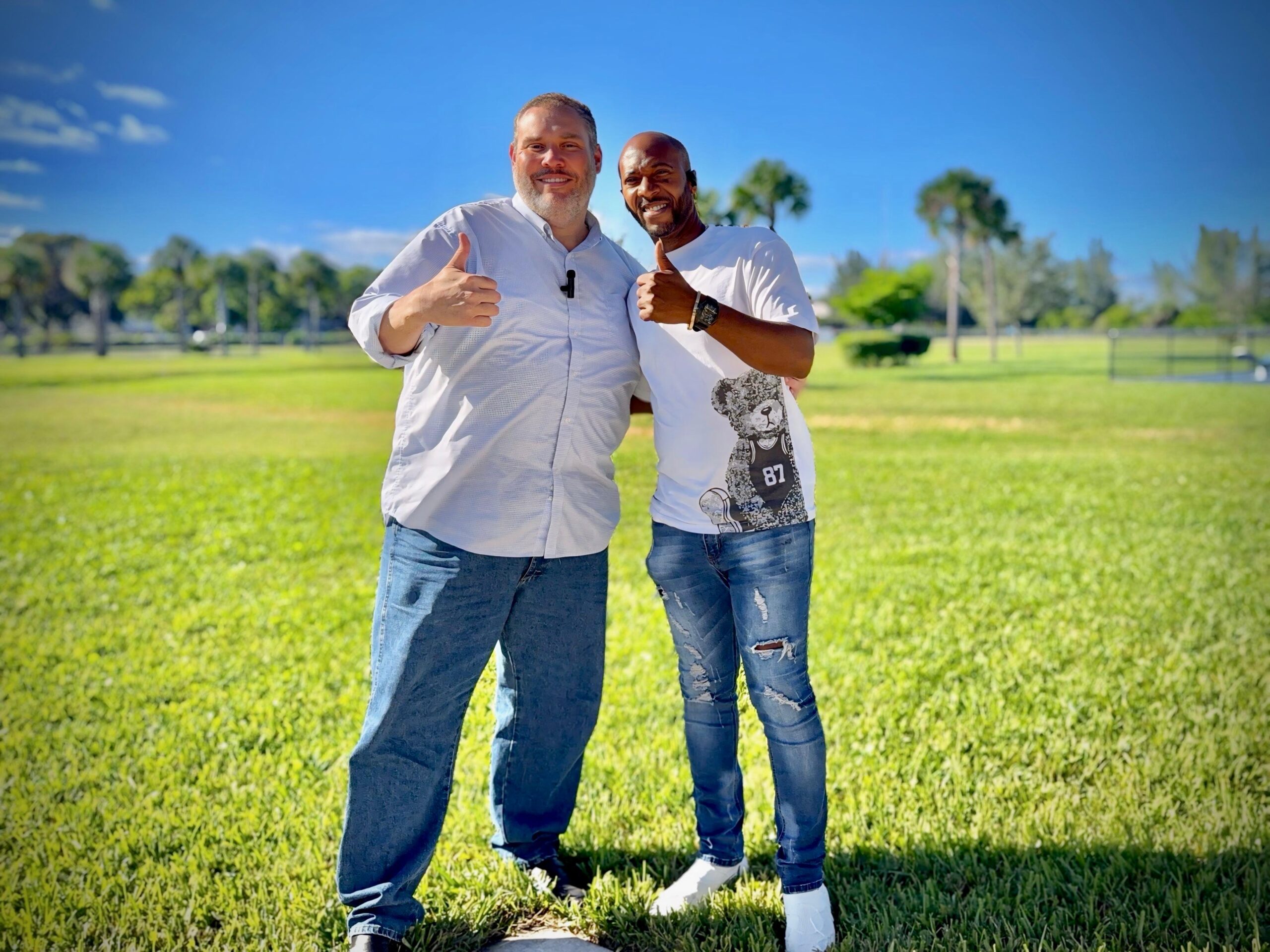 Yadel Marti and Eliam standing looking at the camera and giving a thumbs up
